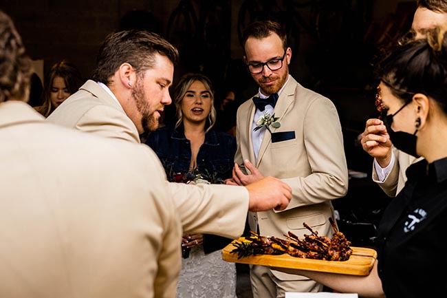 picture of a big grill catering server serving chicken on a wood platter to wedding guests